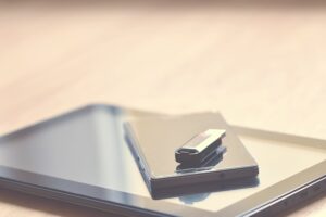 USB flash drive resting on a smartphone and tablet, representing digital forensic services and data recovery tools