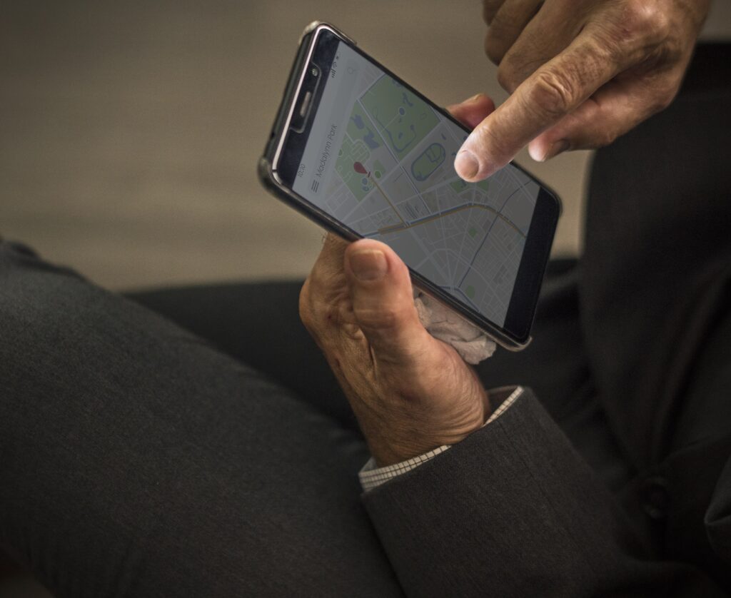 Close-up of a businessman using a smartphone with a digital map, symbolizing legal navigation and criminal defense cases in Cyprus.